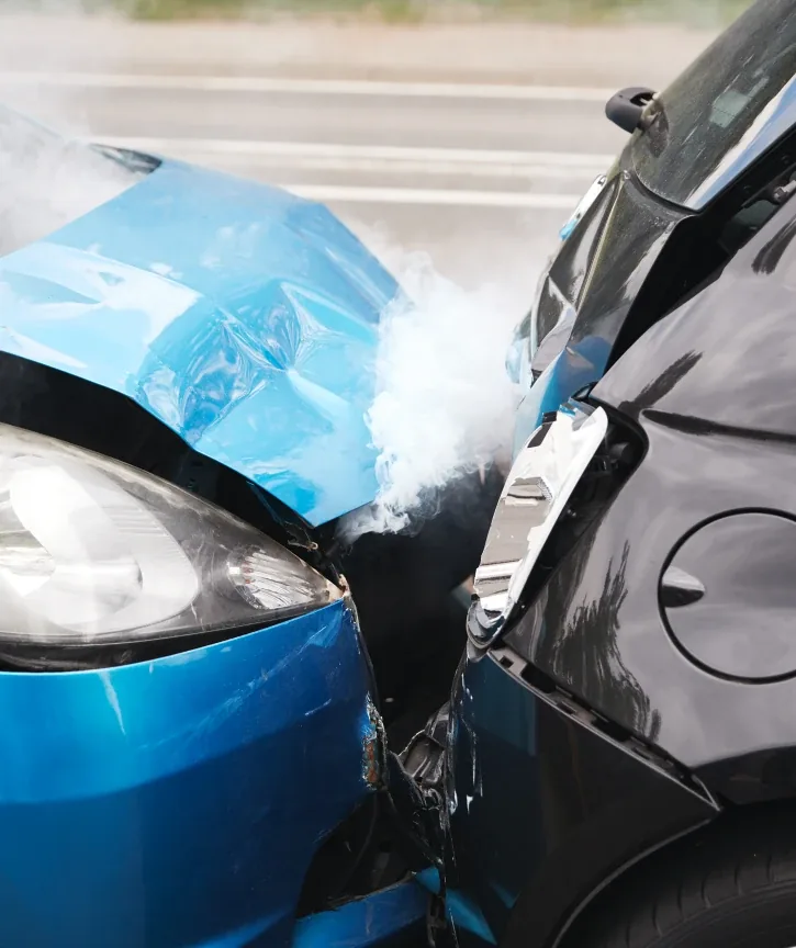 High impact car collision aftermath, crumpled blue and black cars with smoke and damaged fronts