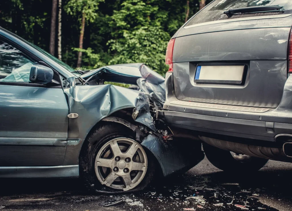Severe rear-end car crash with heavy damage, debris scattered between two parked vehicles