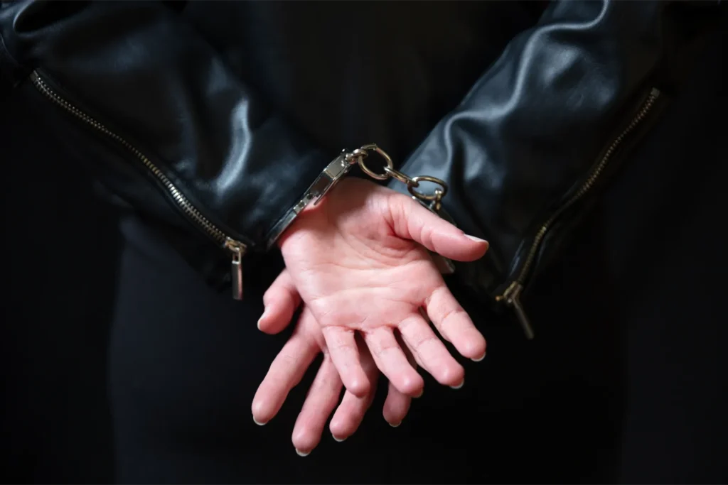 Clasped hands in dark leather cuffs, tense arrest scene with protection and support grip