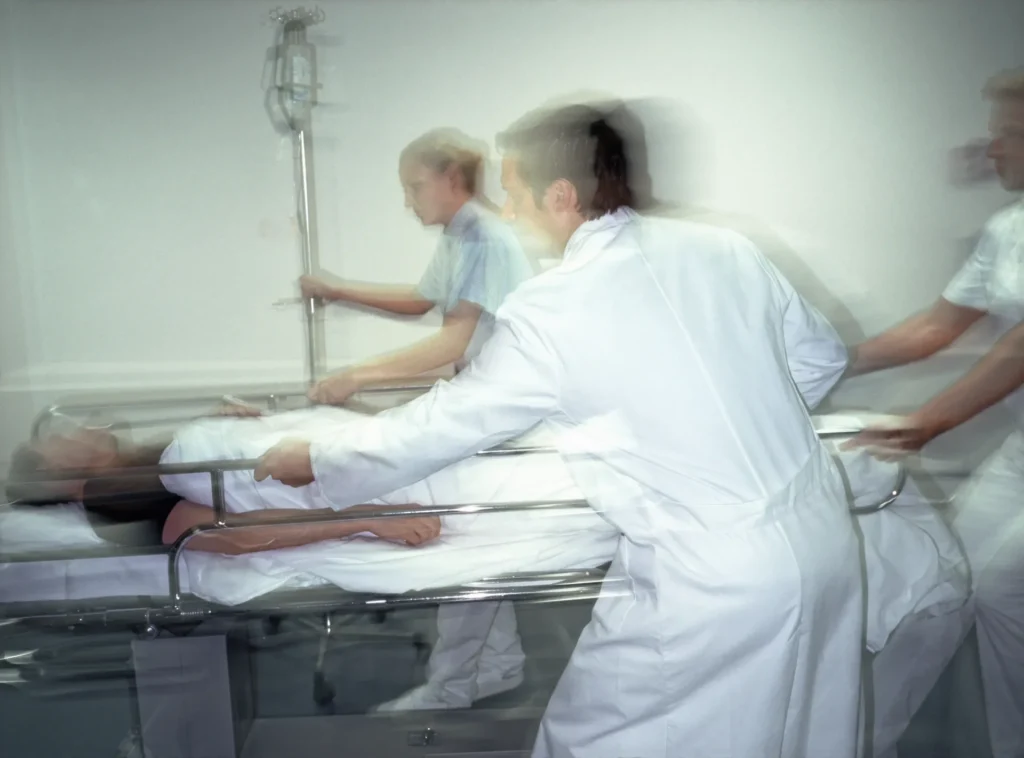 Medical staff assisting elderly patient on treatment bed in hospital care room