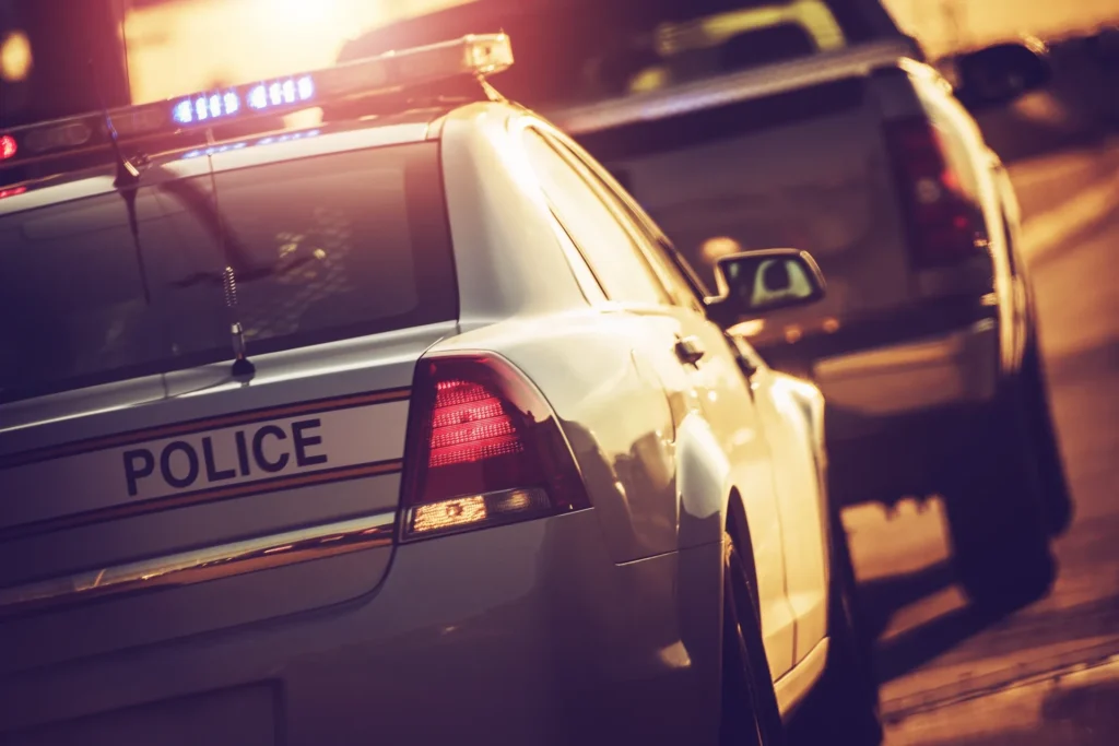 State police car at night during traffic stop, taillights glowing and street lights reflecting
