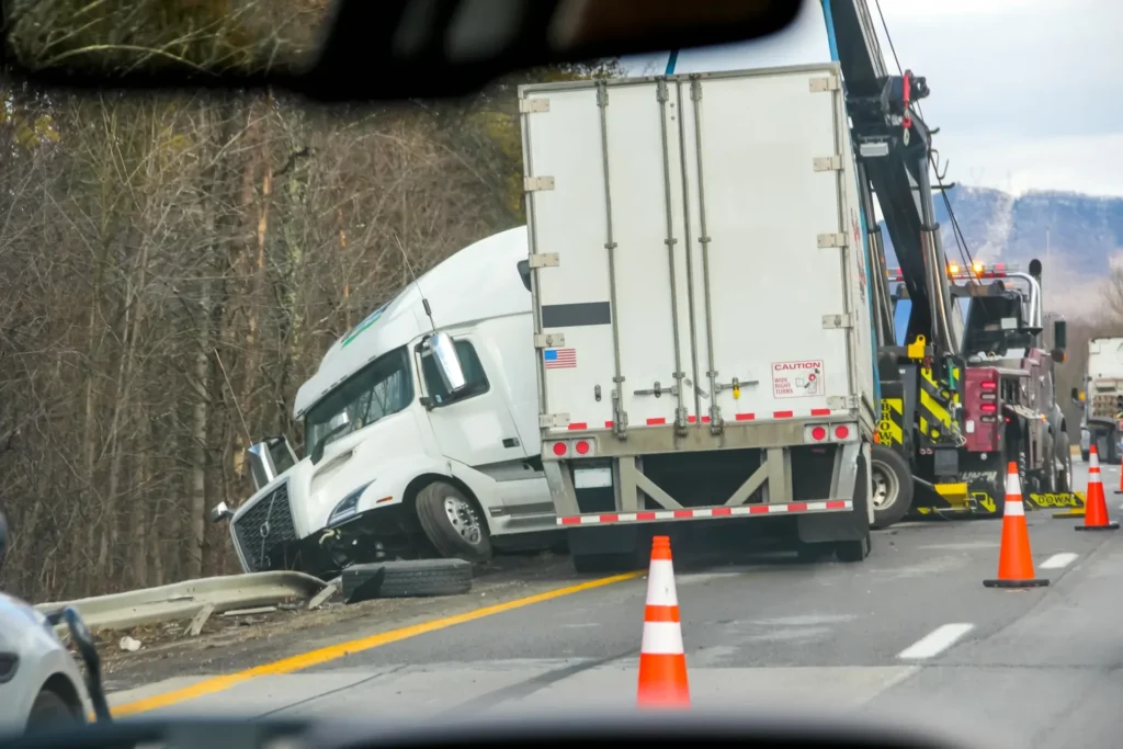 White cargo truck drives through orange cone roadwork in wooded area, traffic control zone