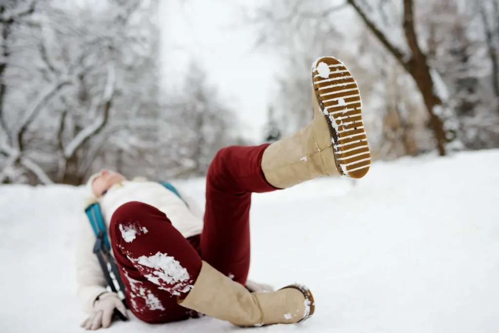 Winter snow slip and fall with two people playing outdoors in snowy park