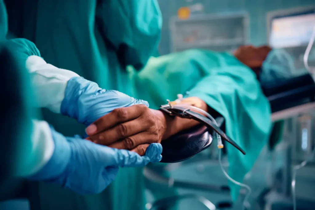 Surgical team secures medical device with gloved hands in clinical operating room procedure.