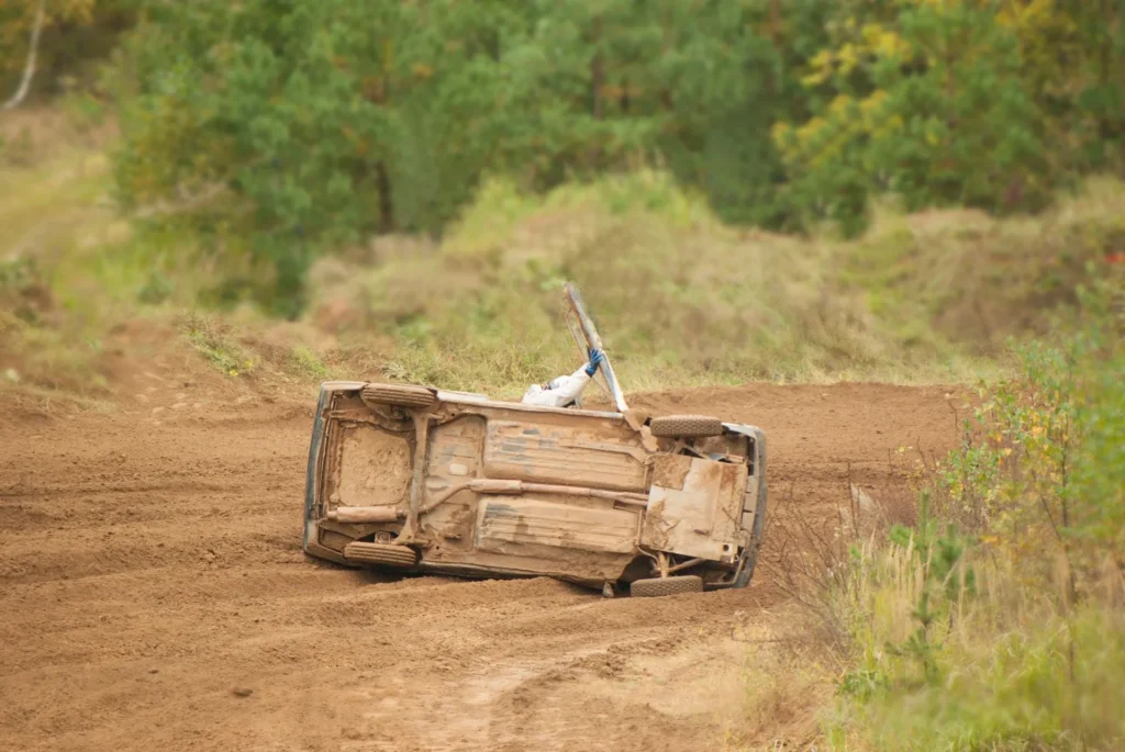Wrecked Utility Truck on Dusty Off-Road Dirt Trail Through Green Shrubs